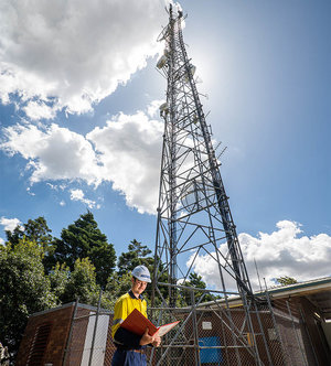 Comtel team member looking at documents in front of communications tower