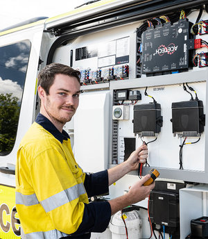 Comtel team member looking at camera smiling while repairing communication gear on Ambulance