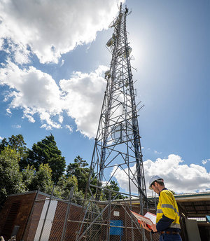 Comtel team member standing in front of communication tower
